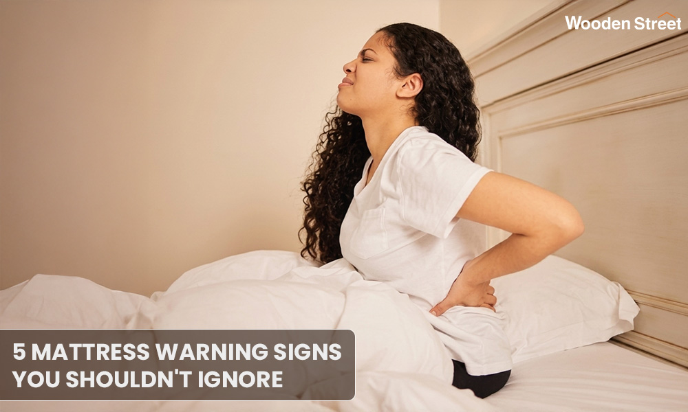 Woman sitting up in bed clutching her painful lower back